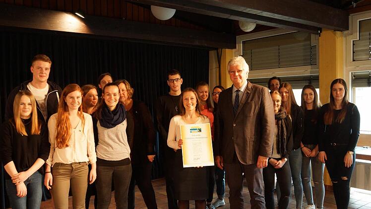 Shiloe Mokay überreicht Direktor Helmut Schreiner im Beisein der P-Seminarschüler die Urkunde.Foto: Arkadius Guzy