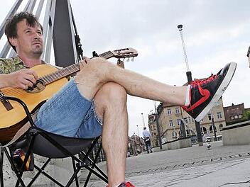 Nun sitzt Moritz Rabe auf der anderen Seite der Kettenbrücke und musiziert weiter. Foto: Matthias Hoch