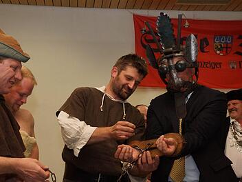 Der Thulbaer Bauernhaufen hat Redaktionsleiter Paul Ziegler erst eine Schandmaske aufgesetzt und legt ihm danach Fesseln an. Fotos: Arkadius Guzy und Kerstin Väth