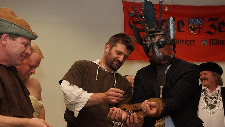 Der Thulbaer Bauernhaufen hat Redaktionsleiter Paul Ziegler erst eine Schandmaske aufgesetzt und legt ihm danach Fesseln an. Fotos: Arkadius Guzy und Kerstin Väth
