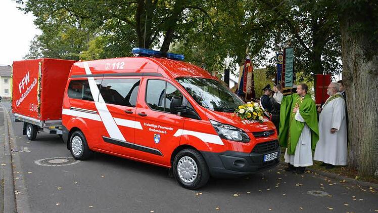 Pfarrer Michael Kubatko weiht das neue Fahrzeug und den Anhänger.