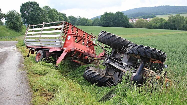 Auf der Seite blieb der Traktor neben dem Feldweg liegen. Der Ladewagen stürzte nicht um. Der Fahrer blieb unverletzt.  Foto: Helmut Will