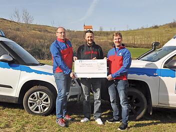 Michael Hahn von den Clubfreunden aus Burk (M.) &uuml;bergibt am Walberla-Plateau den symbolischen Scheck an die Bergwachtler Thomas Obeth und Daniel Lochner (r.). Foto: Leo H&uuml;hnlein