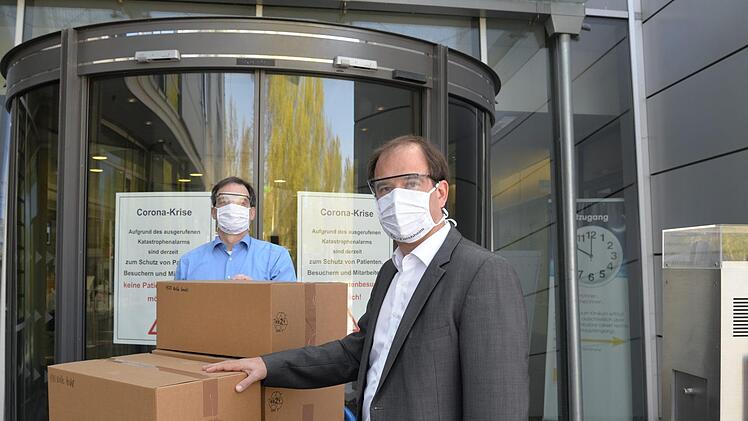 Prokurist Oliver Amon (l.)  dankt vor dem Klinikum in Forchheim Dietmar Drummer f&uuml;r die Lieferung von 1000 Schutzbrillen. Foto: PR