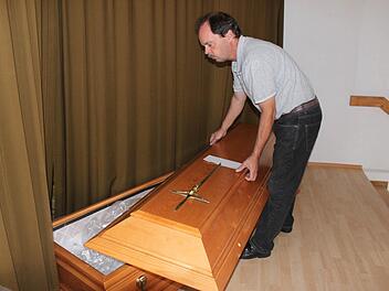 Hans-Georg Hofmann öffnet einen der Särge in seinem Verkaufsraum in Lußberg (Gemeinde Breitbrunn/Landkreis Haßberge). Foto: Friederike Stark