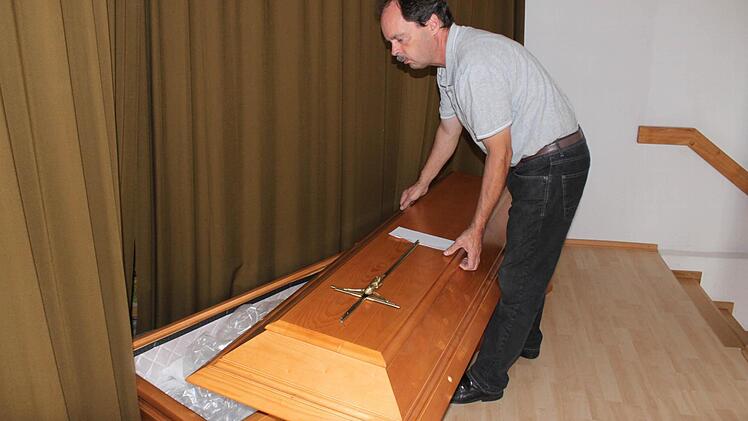 Hans-Georg Hofmann öffnet einen der Särge in seinem Verkaufsraum in Lußberg (Gemeinde Breitbrunn/Landkreis Haßberge). Foto: Friederike Stark