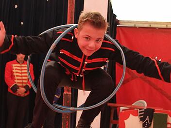 Carlos (12) tritt in der Manege eigentlich als Clown auf, aber er kann auch andere Sachen: Er balanciert auf einer Rolle - und verknotet sich dabei in zwei Hula-Hoop-Reifen. Fotos: Adam