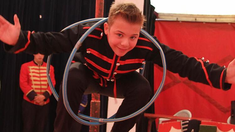 Carlos (12) tritt in der Manege eigentlich als Clown auf, aber er kann auch andere Sachen: Er balanciert auf einer Rolle - und verknotet sich dabei in zwei Hula-Hoop-Reifen. Fotos: Adam