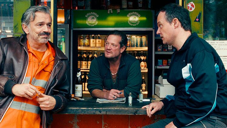 Die alten Schulfreunde  Guido (Alexander Wipprecht, links), Hajo (Aurel Manthei, Mitte) und Thorsten (Johannes Allmayer) leben und philosophieren &uuml;ber weite Strecken des Tages an Hajos Kiosk. Bis ein Koffer ihr Leben ver&auml;ndern k&ouml;nnte.