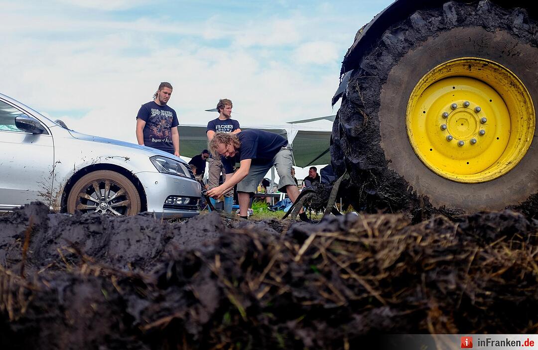 Ein Traktor zieht am 04.08.2016 in Wacken (Schleswig-Holstein) auf dem Gelände des Wacken Open Air ein Auto aus dem Matsch.
