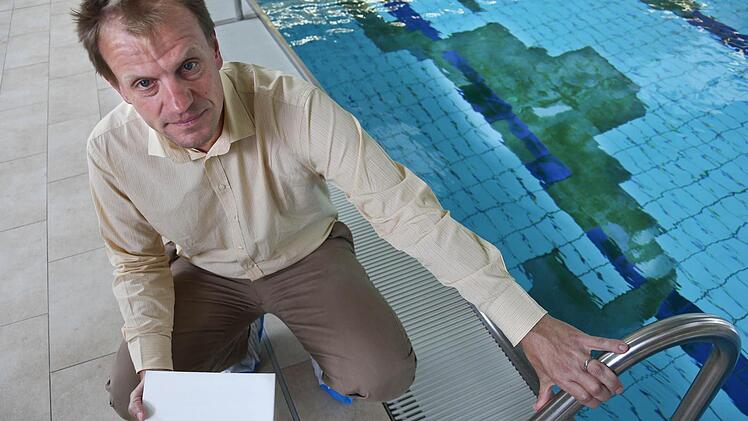 Die weiße Fliese in der Hand statt am Beckenboden: Im Wasser neben Christoph Jeromin ist der Schaden deutlich zu sehen. Foto: Matthias Hoch