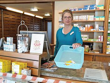 Brigitte Raetsch in ihrer Apotheke in der Mohrenstraße: Das Trassierband vorm Tresen soll die Kunden auf Abstand halten. Rezepte, Medikamente und Geld werden im Korb hin und her gereicht. Fotos: Simone Bastian