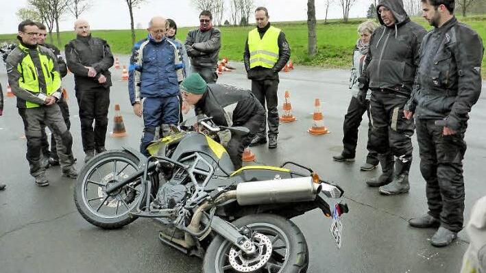 Wenn das Motorrad einmal umkippt, bedarf es besonderer Griffe, um die schwere Maschine wieder auf zwei Räder zu stellen. Fahrlehrer Udo Janke (Mitte vorne) gab dazu fachkundige Tipps. Foto: K.- H. Hofmann