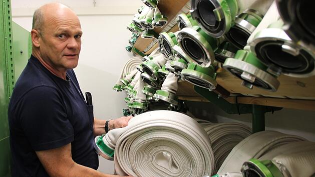 Rainer Schmitt r&auml;umt einen gewaschenen und wieder aufgerollten Schlauch ins Lager. Foto: Benedikt Borst