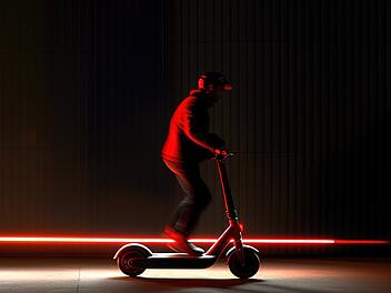 Person riding modern electric scooter at night with copy space
