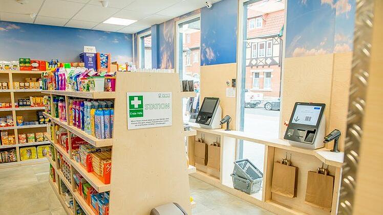 Kund*innen von "Emma's Tag und Nachtmarkt" bezahlen an  Kassenautomaten mit EC- oder Kreditkarte