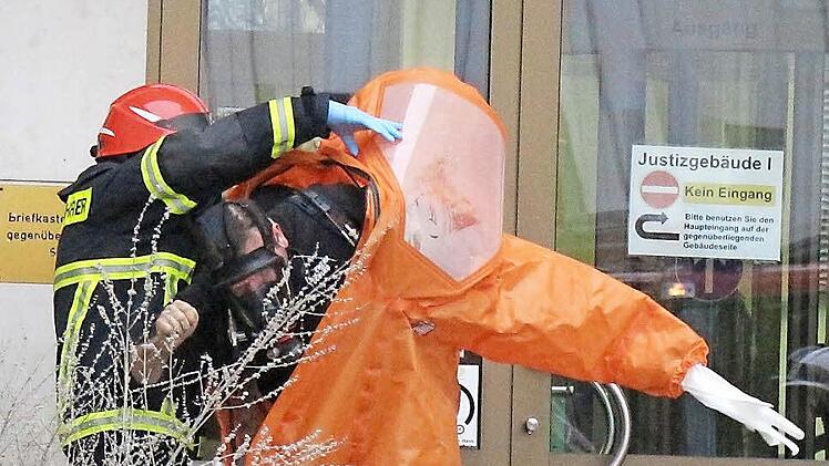 Ein Feuerwehrmann schlüpft am Mittwoch vor dem Justizgebäude in Coburg mit Hilfe eines Kameraden aus einem Einweg-Chemikalien-Schutzanzug. Er und ein Kollege hatten das weiße Pulver sichergestellt. Die Schutzanzüge wurden nach dem Einsatz entsorgt. Ein solcher Anzug mit Handschuhen und Stiefeln kostet 300 Euro. Foto: Simone Bastian