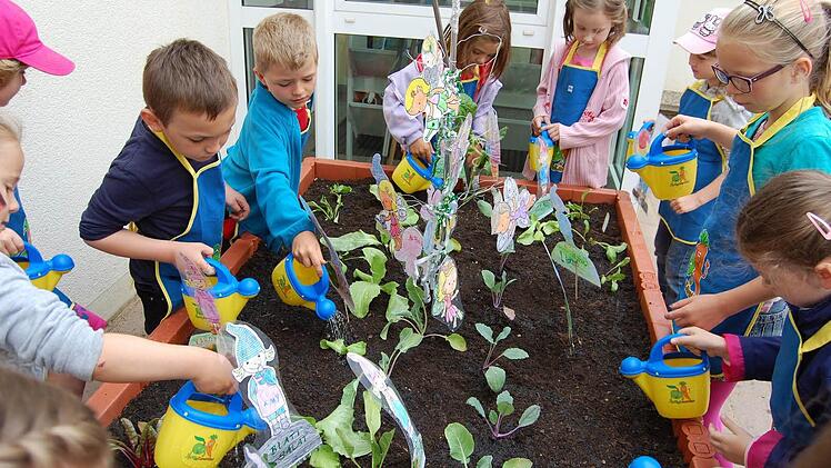 Mit Gießkännchen durften die Kinder die Pflänzchen angießen, nachdem sie die Setzlinge in das Erdreich des neuen Hochbeetes gebracht hatten.  Foto: Günther Straub