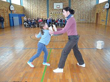 Mit einem kräftigen Stoß zerschmettert Laura das von Trainerin Heike Bittner vorgehaltene Brett. Die Eltern und Gäste applaudierten im Hintergrund.Karl-Heinz Hofmann