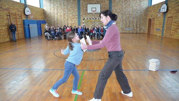 Mit einem kräftigen Stoß zerschmettert Laura das von Trainerin Heike Bittner vorgehaltene Brett. Die Eltern und Gäste applaudierten im Hintergrund.Karl-Heinz Hofmann