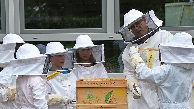 Matthias Reg hilft den Kindern, vorsichtig die Waben aus den Stöcken herauszunehmen.  Foto: Gabi Bertram