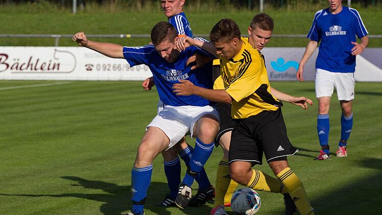 Kasendorfs Florian Luft (blaues Trikot) verliert den Ball an die Frohnlacher Jannik Schmidt (vorne) und Marcel Schöpf (rechts). Hinten SSV-Kapitän Thomas Ellner. Foto: Heinrich Weiß