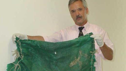 Karl-Heinz Schmitt, der Polizeisprecher, zeigt die grüne Plane, in die der Torso eingewickelt war.