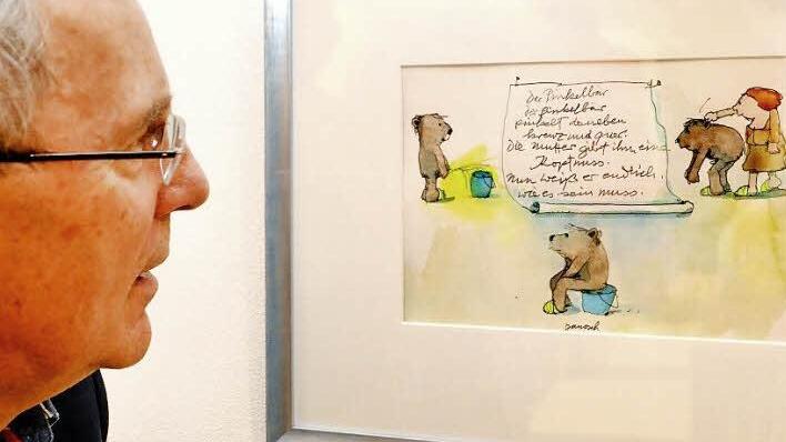 Golfclubpräsident Wolfgang Hertrich vor einer der etwas schelmischen Zeichnungen von Janosch, dem "Erfinder" der Tigerente und ihrer Freunde. Rund 100 Werke aus dem 60-jährigen Schaffen des Künstlers sind bis Ende September in den Räumen des Bad Kissinger Golfclubs ausgestellt.  Foto: Peter Rauch