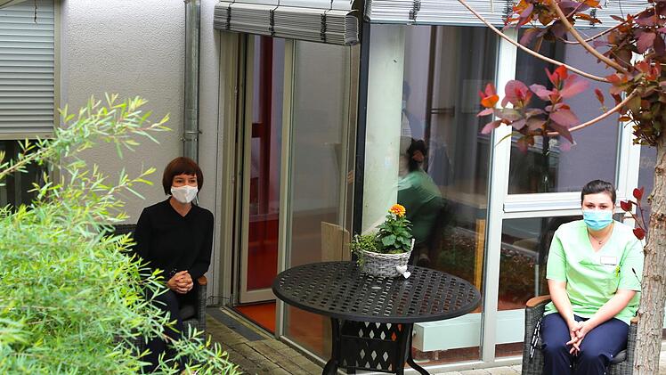 Eine fest definierte Kontaktperson kann im Pflegeheim in der Seßlacher Altstadt zur zuvor festgelegten Uhrzeit und Dauer den Bewohner im Garten treffen, muss aber dabei auf ausreichend Hygiene, Mundschutz und Abstand halten, wie Leiterin Diane Alka (links) und Schwester Tanja hier demonstrieren. Bei schlechtem Wetter steht der Raum dahinter für eine Begegnung zur Verfügung.  Fotos: Bettina Knauth