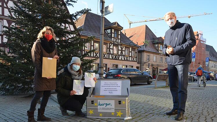 Eva Bauer und Anna-Lena Gumbrecht zeigen Bürgermeister German Hacker die Adventskiste mit den kleinen Geschenken für die Familien.