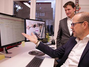 Die Geschäftsführer Udo Reppert (stehend) und Marcellus Scheefer recherchieren in der Datenbank von Pro Care Management den CO2-Fußabdruck verschiedener Lebensmittel.