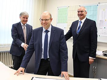 Die Schulleiter Herbert Brunner (Alexandrinum, links) und Burkhard Spachmann (Casimirianum, rechts) rücken dem designierten Direktor des Alexandrinums, Stephan Feuerpfeil, den Chefsessel zum Probesitzen zurecht. Ab 16. Februar ist dies dann Feuerpfeils Büro.Ulrike Nauer