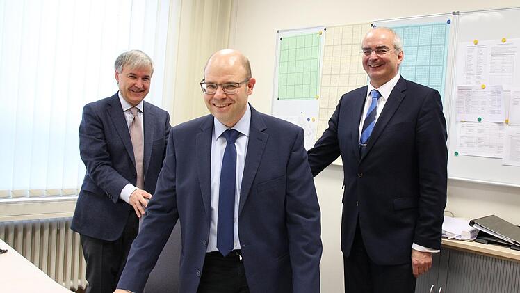 Die Schulleiter Herbert Brunner (Alexandrinum, links) und Burkhard Spachmann (Casimirianum, rechts) rücken dem designierten Direktor des Alexandrinums, Stephan Feuerpfeil, den Chefsessel zum Probesitzen zurecht. Ab 16. Februar ist dies dann Feuerpfeils Büro.Ulrike Nauer
