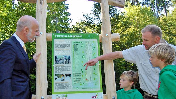 Oberbürgermeister Kay Blankenburg (links) und Schüler des Kissori-Lernzentrums lassen sich an der Informationstafel von Stadtförster Axel Maunz den neuen "Baumpfad Langewiese" erklären.