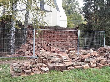 Ein Großteil der Steine der Kirchenmauer ist schon abgetragen und sortiert. Es wird momentan am Wegesrand gelagert. Das vorhandene Material soll später beim Aufmauern wiederverwertet werden.  Foto: Rolf Pralle