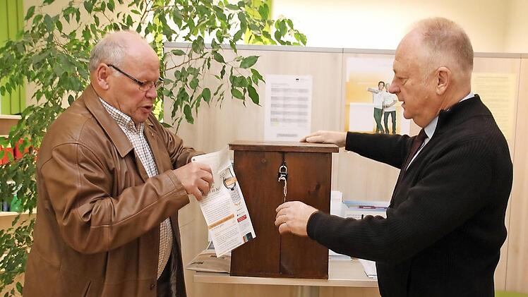 Albert Laudensack (links) tütet ein Handy ein. Nach Rücksprache mit Bürgermeister Helmut Blank sind im Rathaus und im Schloss Wahlurnen als Spendenboxen für alte Handys aufgestellt worden. Fotos: Thomas Malz