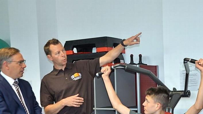 Vorführung an einem Krafttrainingsgerät im neuen Fitnessraum an der Realschule: Der Schüler Tim Maier trainiert, sein Lehrer Felix Pitroff erklärt und Landrat Alexander Tritthart lauscht.  Fotos: Bernhard Panzer