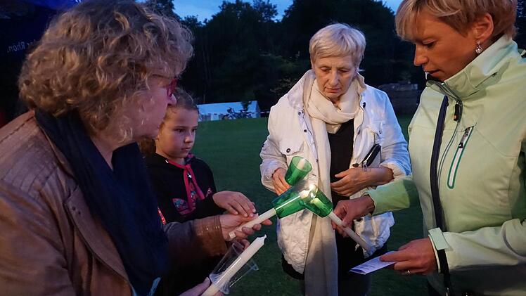 Die Gläubigen geben vor der Prozession um die Kirche am Vorabend des Mariä-Himmelfahrtstages das Licht von Kerze zu Kerze weiter.