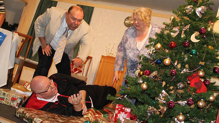 Schöne Bescherung: Werner (Hermann Zeis) und Babs (Silvia Klitzner) sind entsetzt, während Babs Ex-Mann Lutz (Mitte, Norbert Dietz) mitten in den Geschenken liegt. Foto: Gerda Völk
