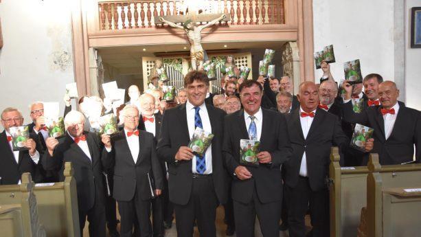 In Ostheim wurde wohl ein neuer Ohrwurm geboren: Das neue Frankenlied "Die Schöppli aus Franken" mit dem mitreißenden Refrain "Schütt‘ de Brüh‘ noo" von  Kilian Moritz (links vorne) stieß beim Männerchor des Fränkischen Sängerbundes (rechts Chorleiter OStR Hermann Freibott) und Publikum auf helle Begeisterung. Foto: Tonya Schulz