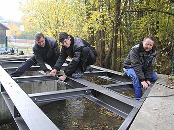 Die neue Brücke wird mit zwölf Gitterrosten belegt - jedes Gitterrost wiegt 80 Kilo. In nur einem Tag ist die neue Konstruktion fertig montiert: Daniel Vetter, Raphael Schimmel und Klaus Wollnik montieren die Maßanfertigung. Fotos: Sonja Adam