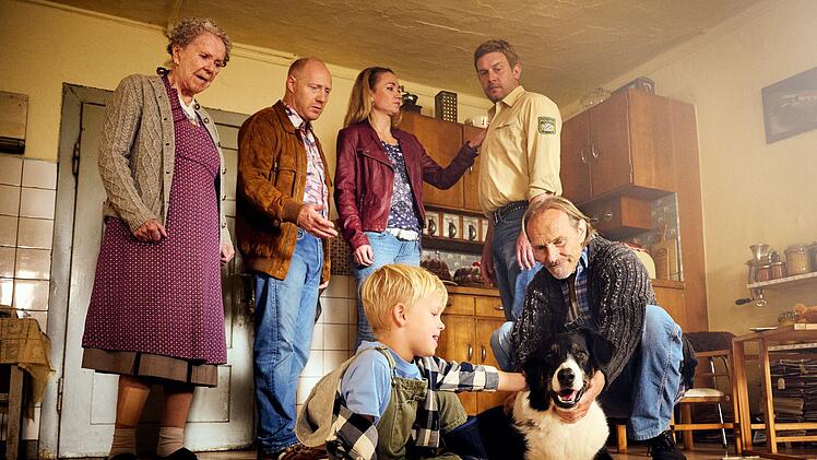 Der Rudi (Simon Schwarz, zweiter von links) hat seinem Spezl Franz (Sebastian Bezzel, zweiter von rechts) etwas mitgebracht: Hund Hinkelotta. Doch im Gegensatz zur Oma (Enzi Fuchs, links), Susi (Lisa Maria Potthoff), Pauli (Luis Sosnowski, dritter von links) und Papa Eberhofer (Eisi Gulp), kann sich der Polizist so gar nicht dar&uuml;ber freuen.