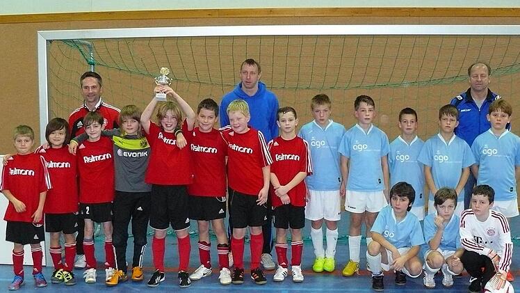 Hoch den Pokal. Die Jungs des FC Neuenmarkt (links) freuen sich über den Turniersieg bei den E 1-Junioren. Mit Platz zwei mussten die Spieler des Veranstalters FC Marktleugast (rechts) nach dem Siebenmeterschießen zufrieden geben. Fotos: Klaus-Peter Wulf