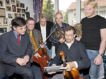 Martin Timphus (vorne Mitte) zeigt seinen Kollegen Christian Dibbern (Zweiter  von links), Wolfgang Braun (Vierter von links) und Christoph Eß (rechts)  vor dem Abflug nach Japan Bilder von seinem Freund Yuichi Sugiyama, der den Musikern beim Organisieren des Onagawa-Konzerts geholfen hat (kleines Bild). Volle Unterstützung bekommen die Musiker von Intendant Wolfgang Fink (links) und Rolf-Peter Hoenen. Foto: Peter Eberts