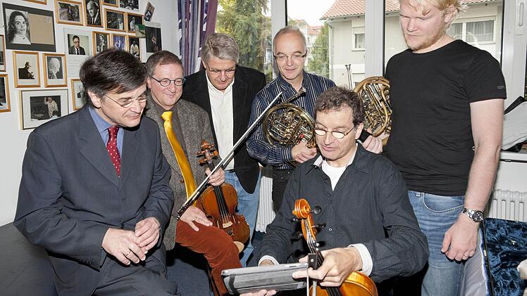 Martin Timphus (vorne Mitte) zeigt seinen Kollegen Christian Dibbern (Zweiter  von links), Wolfgang Braun (Vierter von links) und Christoph Eß (rechts)  vor dem Abflug nach Japan Bilder von seinem Freund Yuichi Sugiyama, der den Musikern beim Organisieren des Onagawa-Konzerts geholfen hat (kleines Bild). Volle Unterstützung bekommen die Musiker von Intendant Wolfgang Fink (links) und Rolf-Peter Hoenen. Foto: Peter Eberts