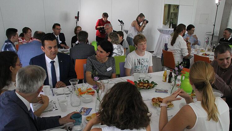 Boulent Ekrem erläuterte die Positionen der FDP am Tisch. Die Leiterin der Montessori-Schule Erlangen, Karin Reif, folgt dessen Ausführungen gespannt. Im Hintergrund diskutiert Joachim Herrmann angeregt (rechts am hinteren Tisch).