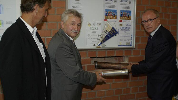 Architekt Thomas Ruser, Bürgermeister Peter Hart und Rektor Hubert Voll (von links) legten die Urkunde und einige Zeitzeugnisse in die Mauer der Schulaula.  Foto: Winfried Ehling