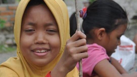 Ein Mädchen auf Sumatra stopft gesammelten Plastikmüll in eine alte Plastikflasche: So entsteht ein Eco-Brick.