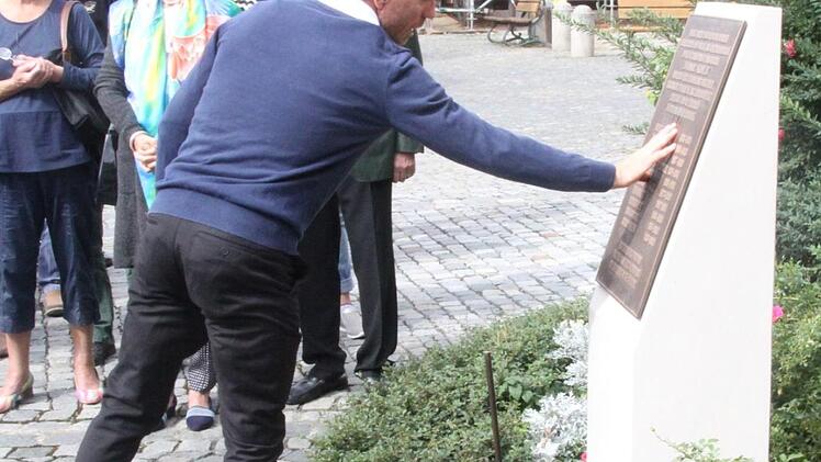 Der Historiker Mark Deavin benetzt das Mahnmal mit Wasser. Die Symbolik des "Taufwassers" auf diesem Stein konnte von allen Besuchern vollzogen werden.  Fotos: Michael Busch