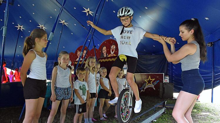 Zirkus macht Spaß. Dies kann auch die zehnjährige Lena Weigl aus Haßfurt bestätigen, die gelernt hat, mit dem Einrad über die Slackline zu fahren. Rechts im Bild die Trainerin Chiara Lauenburger vom gleichnamigen Circus. Foto: Ulrike Langer